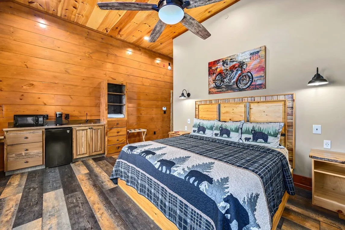 Cabin bedroom before restaging  - bear-themed bedding, motorcycle wall art, empty shelves, generic furnishings