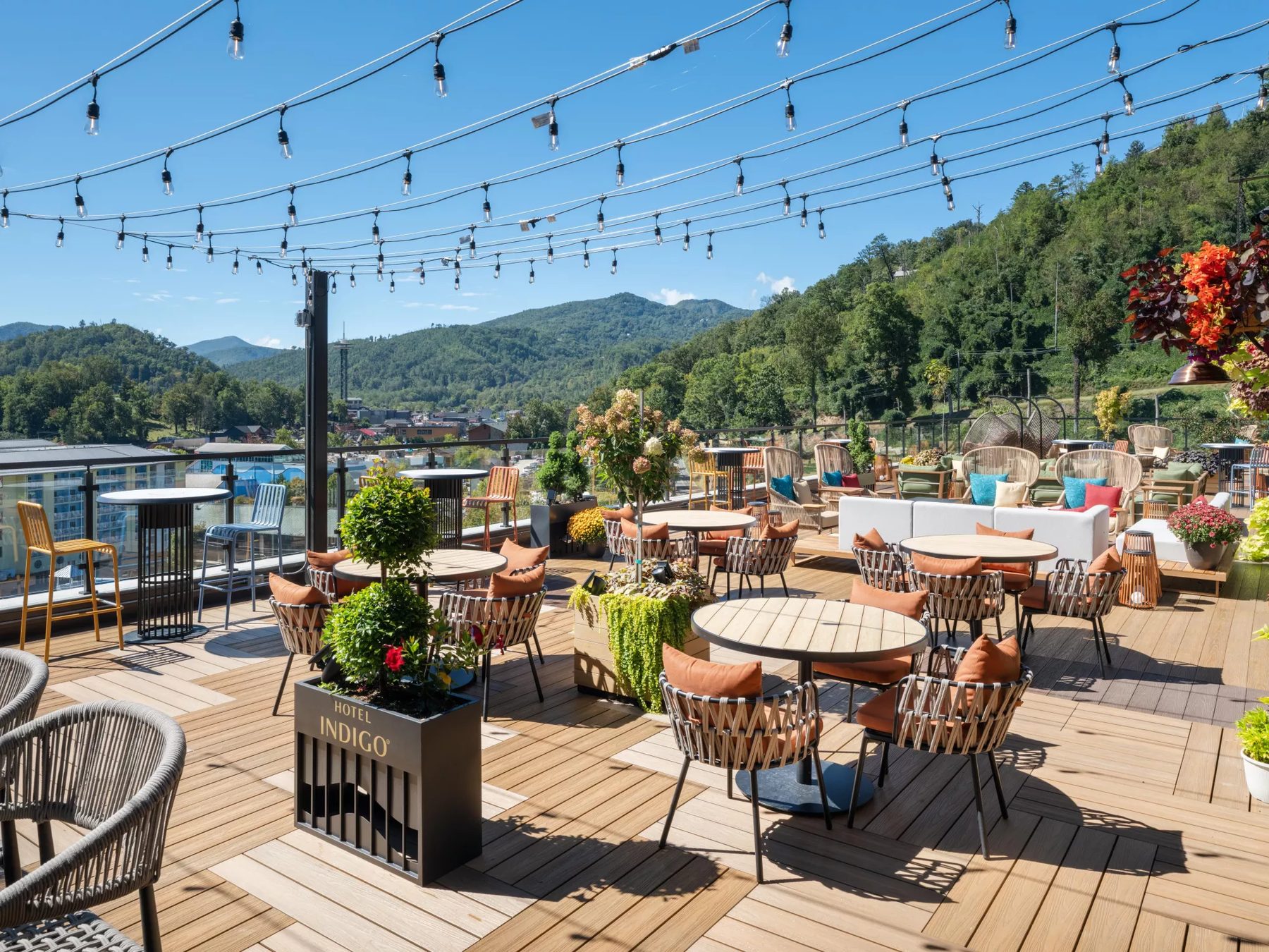 Outdoor patio of Altitude Rooftop Bar with string lights, lounge seating and a view of the mountains above Gatlinburg