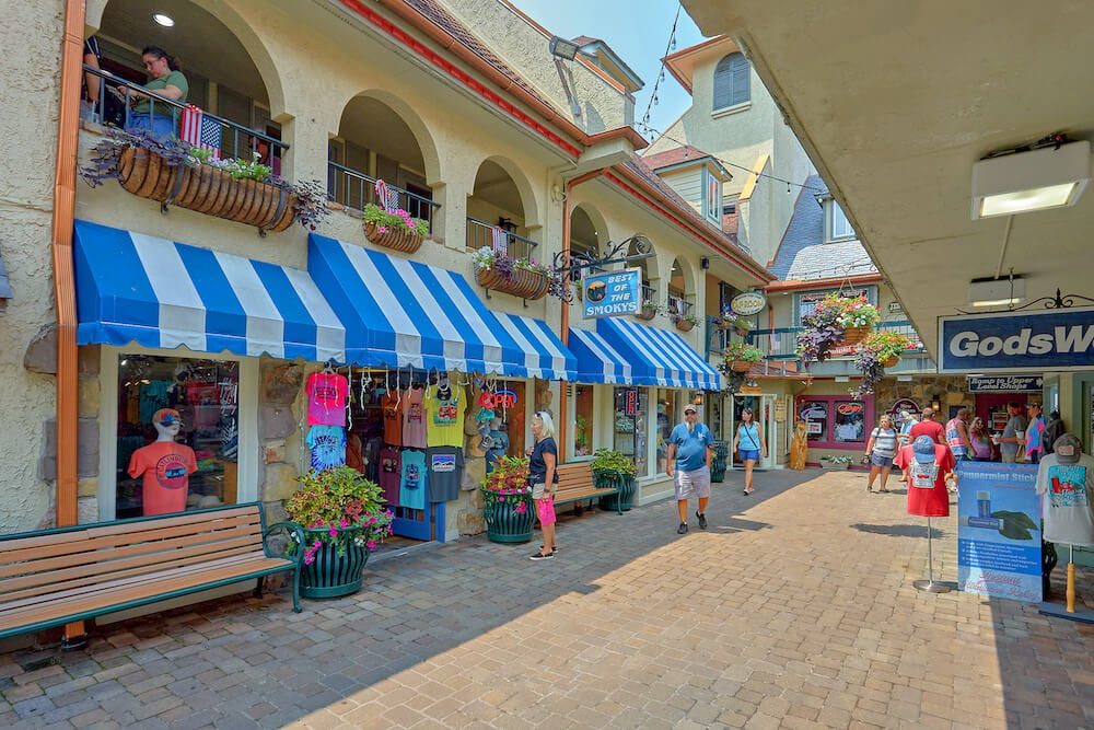 Brick-paved Baskins Square courtyard in Gatlinburg lined with striped awnings and shop fronts