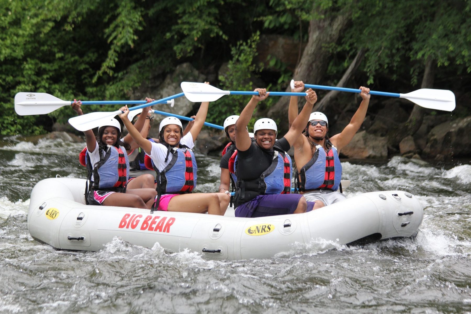 Rafters raising their paddles in a Big Bear raft on the Pigeon River rapids