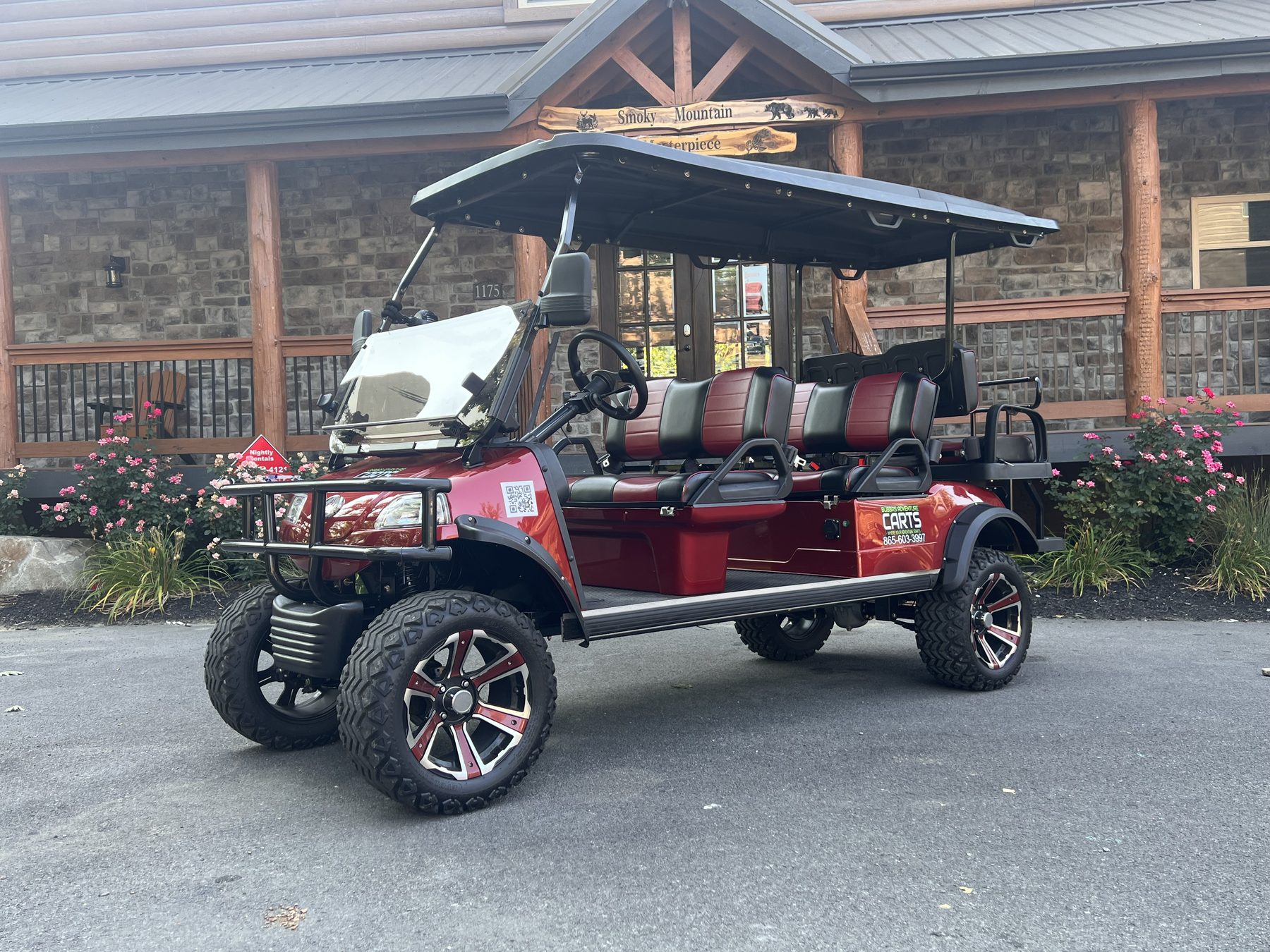 Red six-seat street-legal golf cart parked in front of a stone and timber building in Pigeon Forge