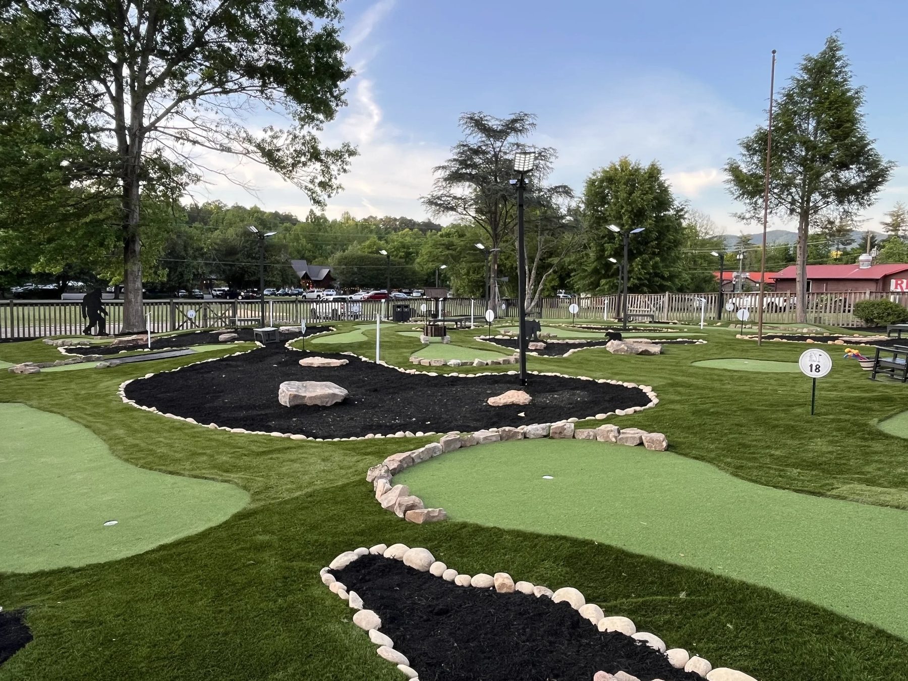 Mini golf course at Cades Cove Golf in Townsend with artificial-turf greens, rock borders and mature trees