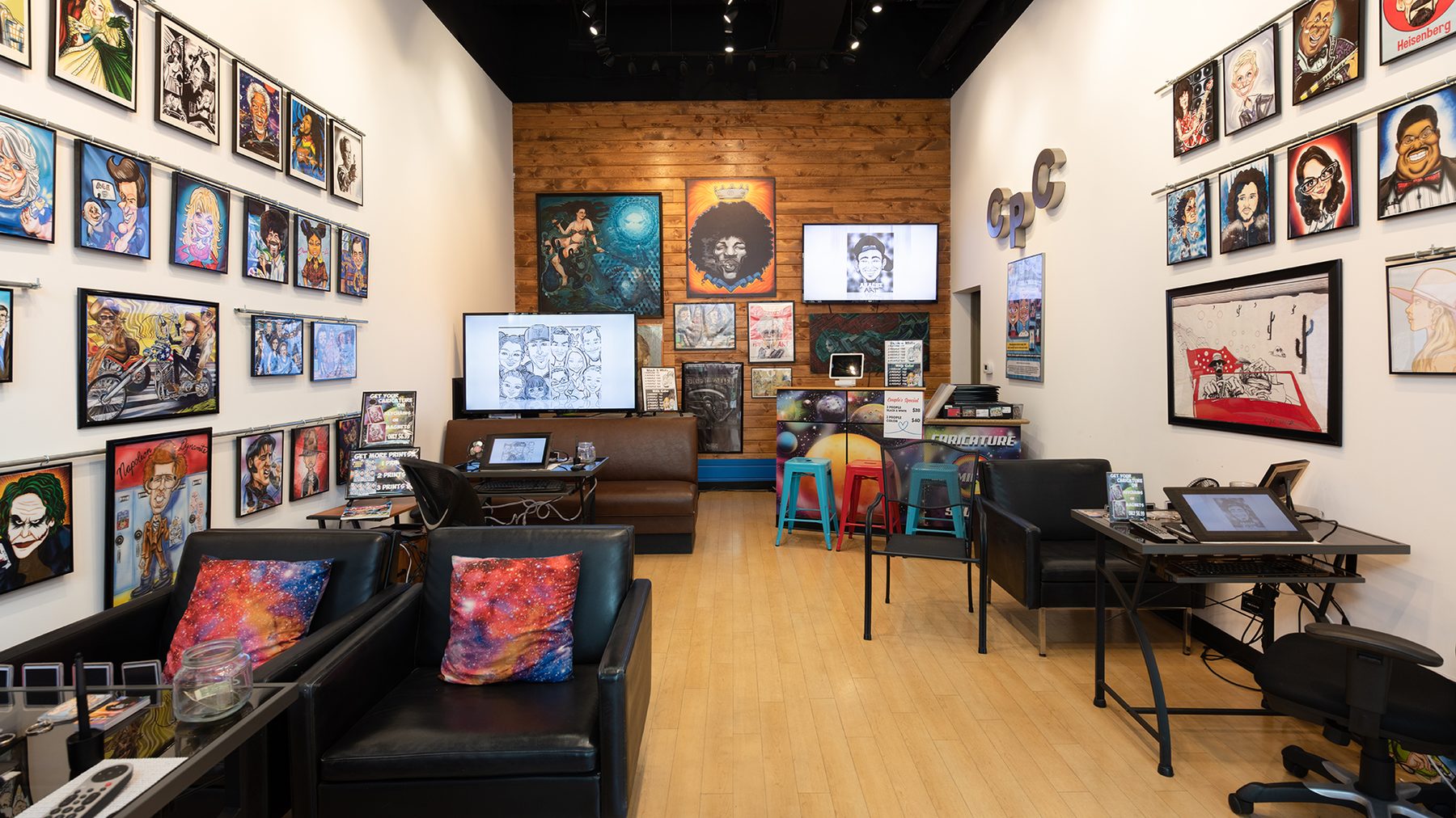 Interior of The Cosmic Pen caricature studio with framed caricatures lining the walls and artist drawing stations