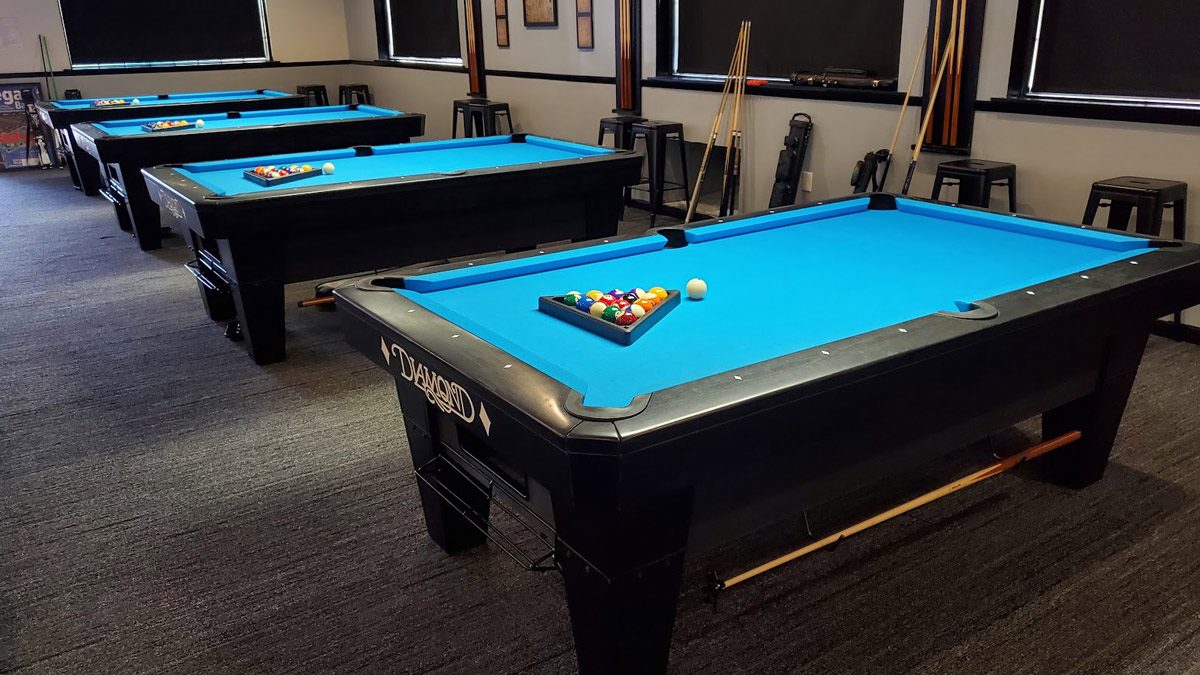 Row of blue-felt pool tables inside East Tennessee Billiards