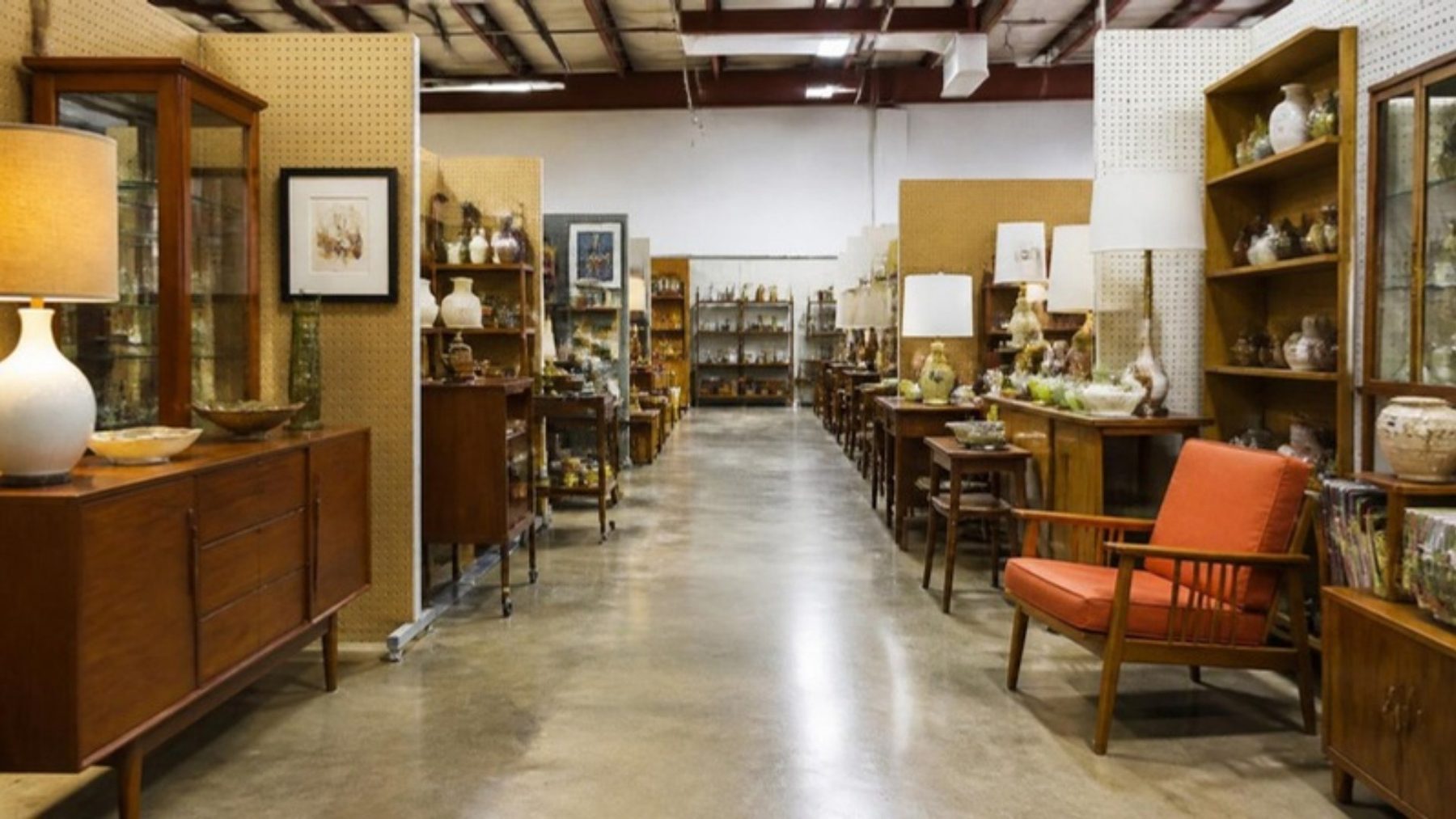 Bright, clean aisles of an antique vendor mall with mid-century furniture, lamps, glassware and collectibles