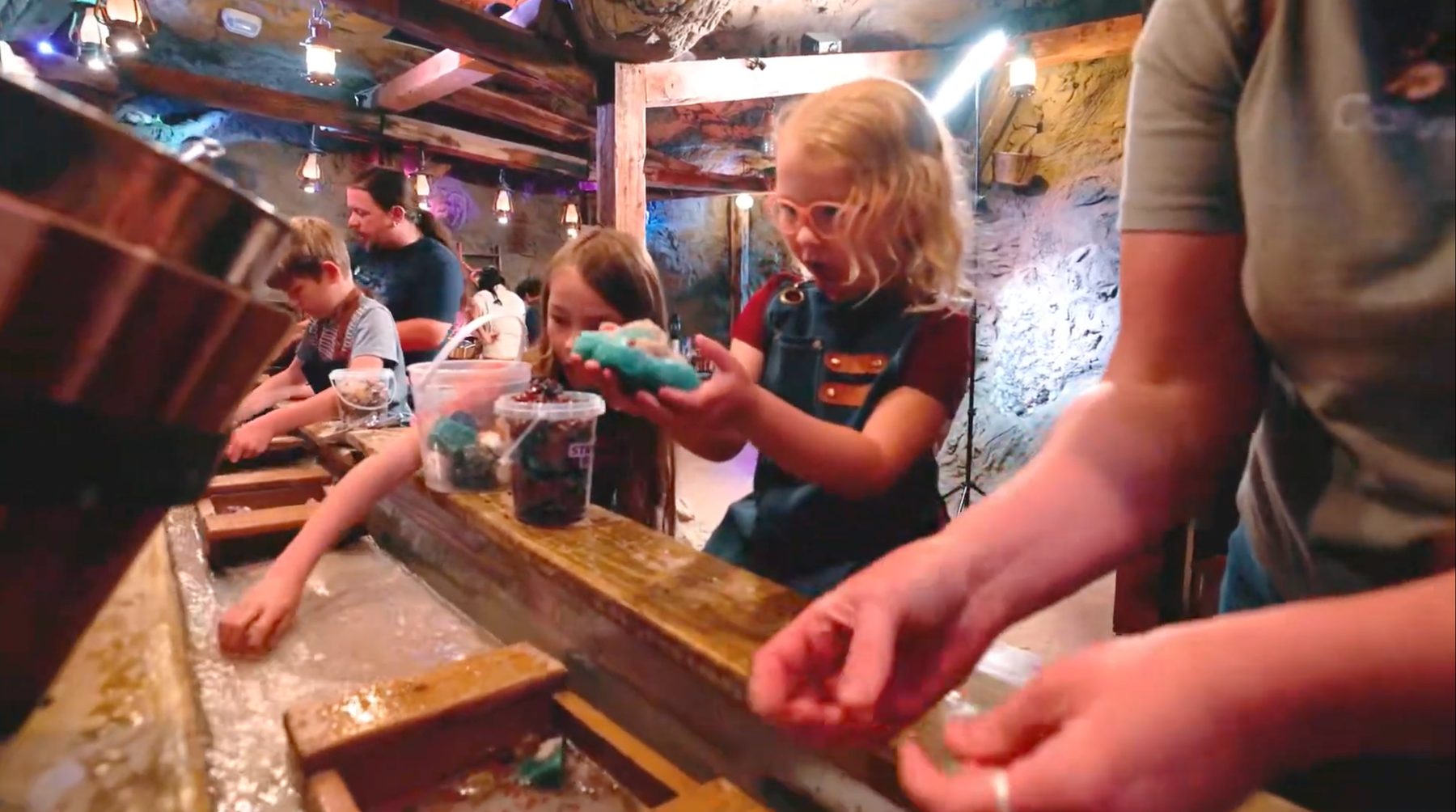 Visitors sifting for gems at the wooden water flume inside Gatlinburg Adventure Mining