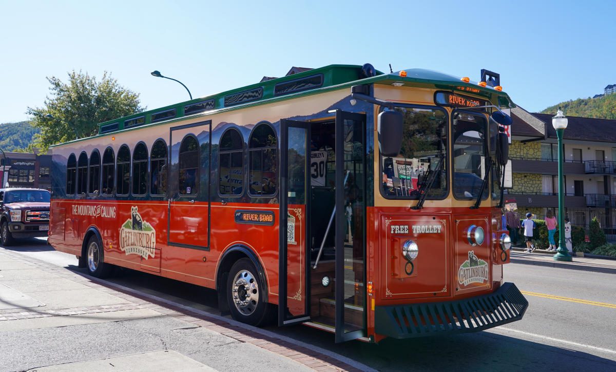 Red Gatlinburg trolley stopped at the curb on the Parkway with its doors open