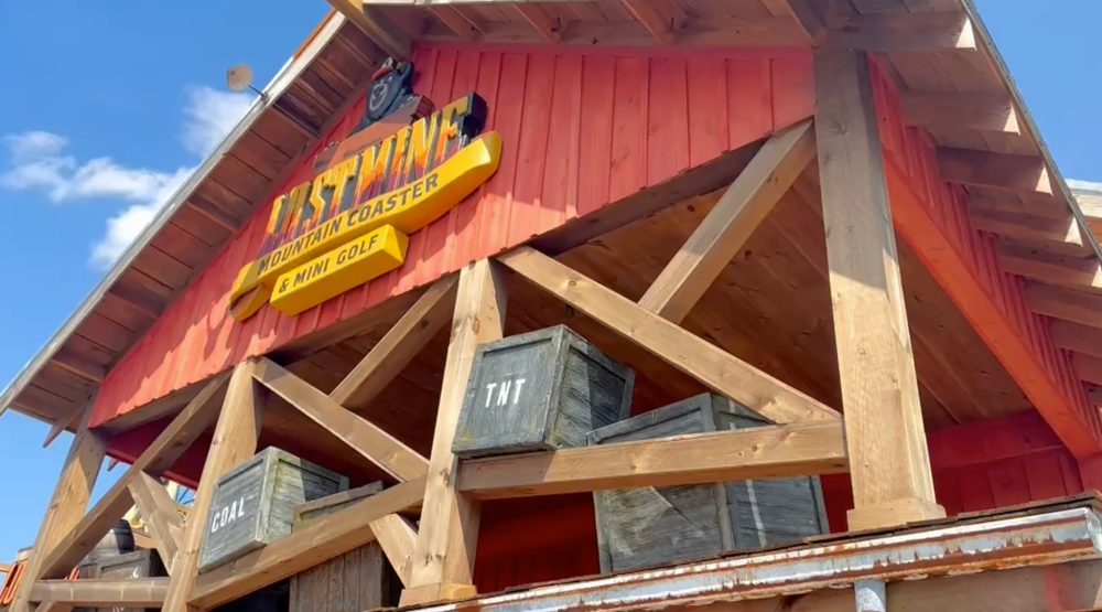 Red barn-style entrance building of Lost Mine Mountain Coaster & Mini Golf with its sign and mining crates