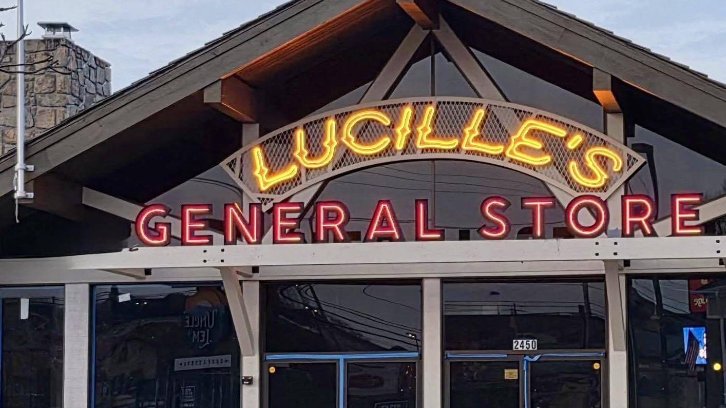 Timber-framed storefront of Lucille's General Store with its lit neon sign on the Parkway in Pigeon Forge