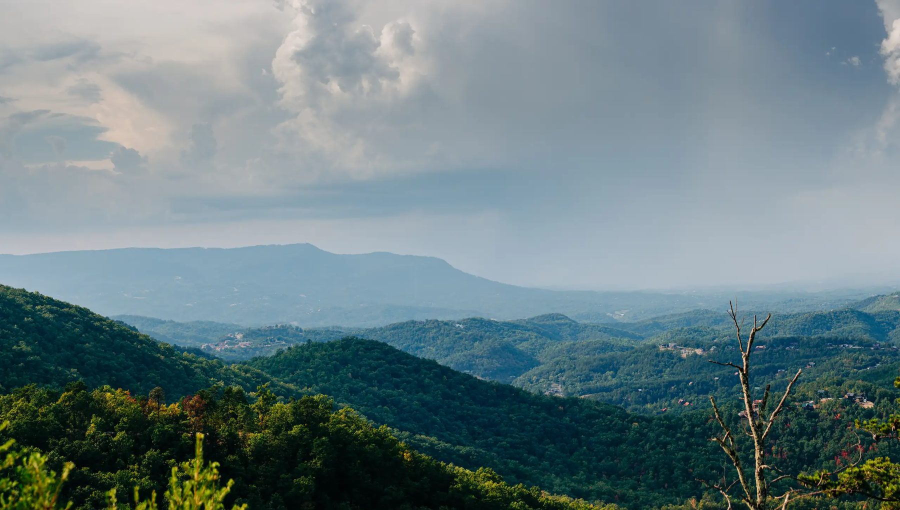 Layered green ridges and storm clouds seen from the WildSide mountaintop, home of MegaZip, above Pigeon Forge