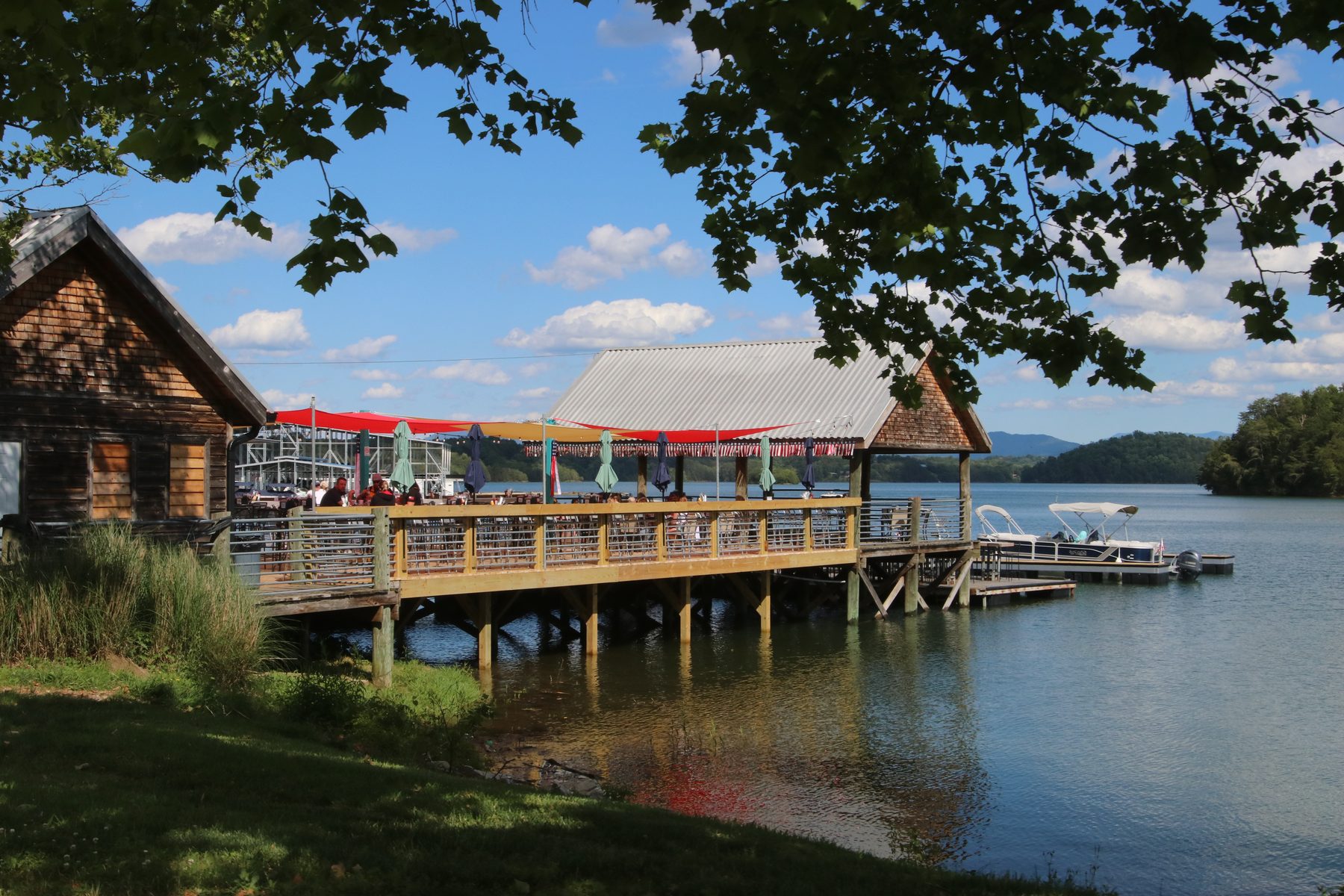 Over-water deck and pavilion of Otters Cove Bar & Grill on Douglas Lake seen through shade trees