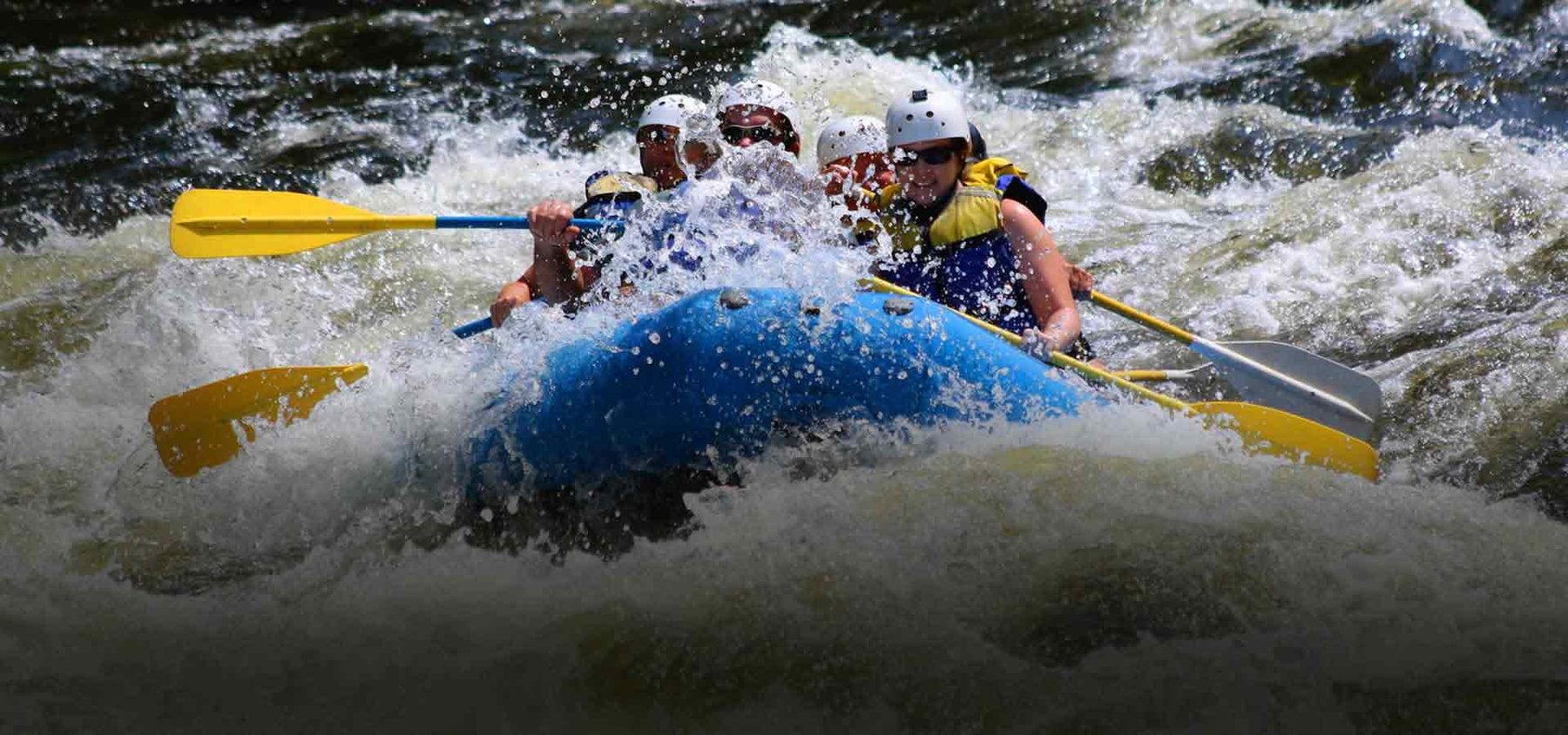 Blue raft full of paddlers punching through whitewater on the Pigeon River