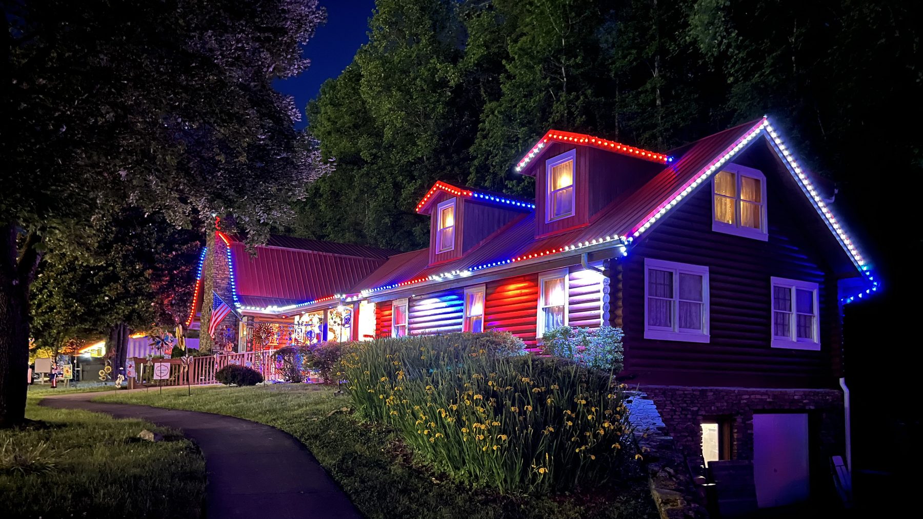 Santa's Claus-et log-sided shop outlined in colored Christmas lights at dusk