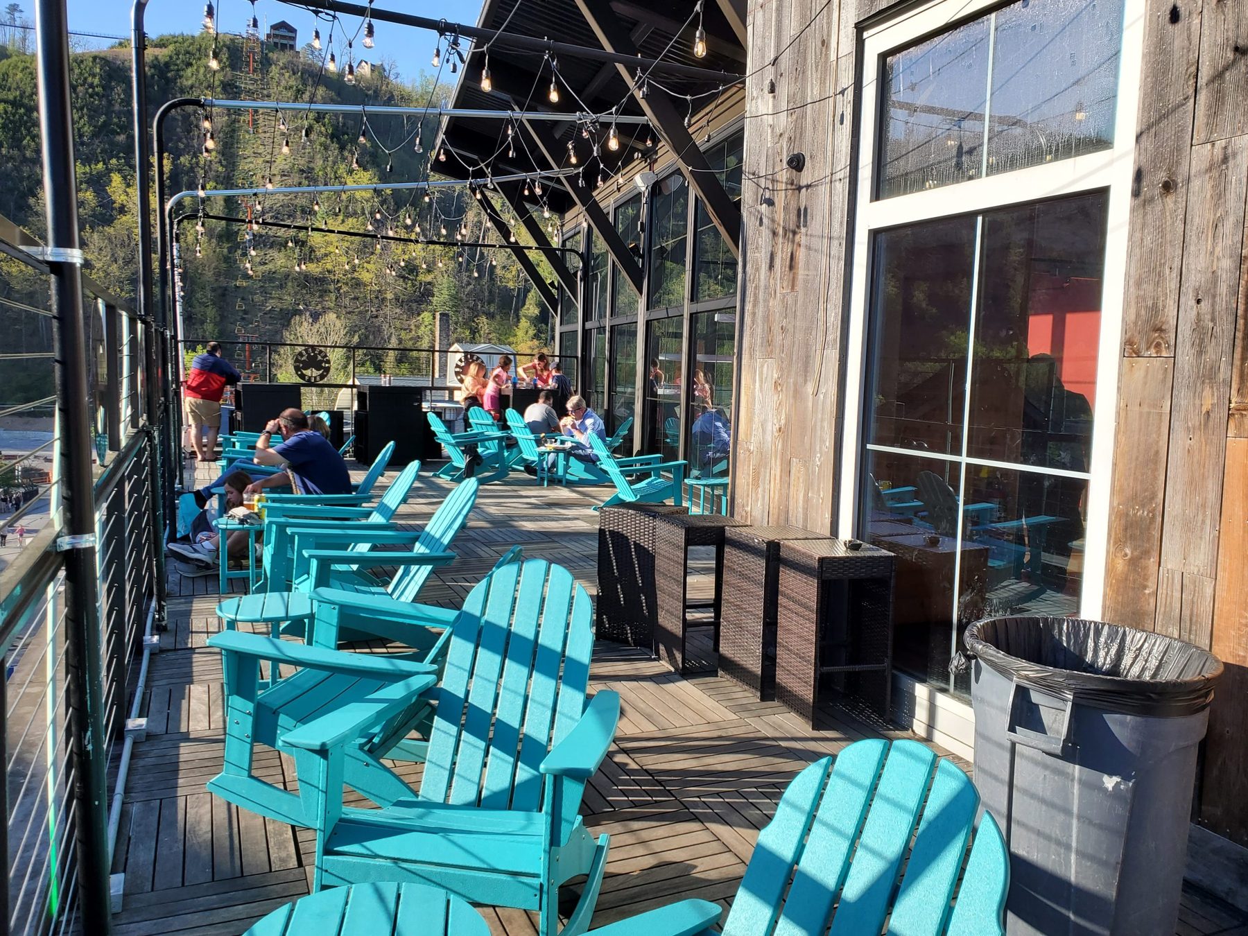 Covered outdoor deck at Shamrock Pub with turquoise Adirondack chairs overlooking the Gatlinburg hillside
