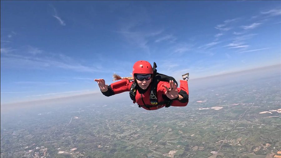 Skydiver in a red jumpsuit and helmet in freefall high above the East Tennessee countryside