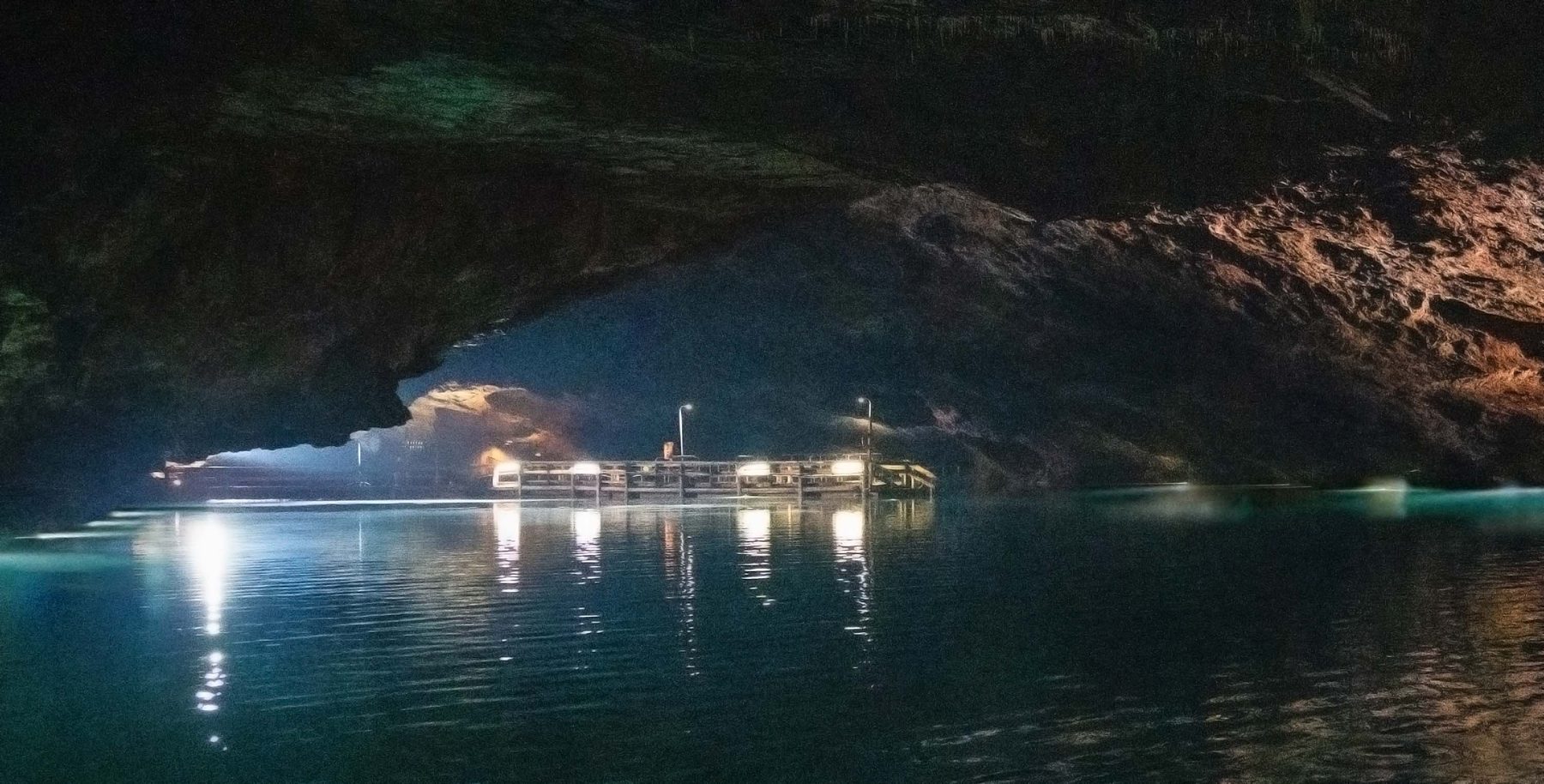 The lit underground lake inside Craighead Caverns at The Lost Sea, with tour boats docked under the cave ceiling